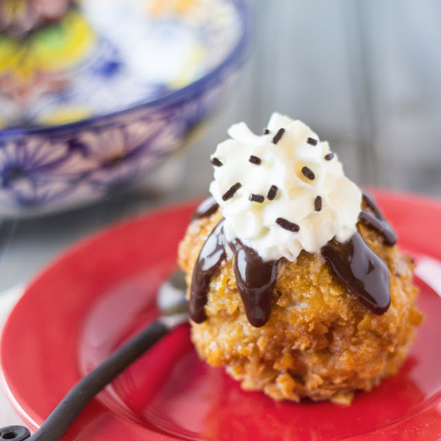 fried ice cream topped with whip cream and chocolate sauce on a red saucer