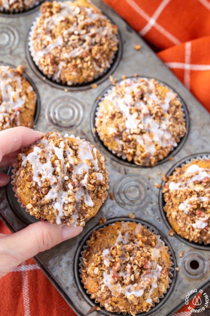 a hand taking a muffin out of a tin