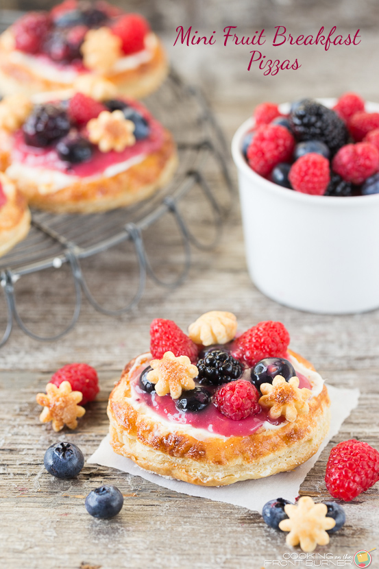 These mini fruit pizzas with fresh berries are sure to be a hit at your breakfast or brunch table fruit berry pizza on a piece of white parchment paper