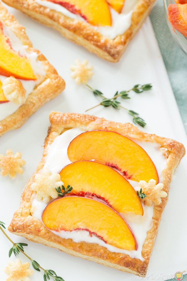 fresh peach tart on a white board with strands of fresh thyme