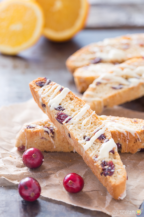 two orange cranberry biscotti stacked; white chocoalte drizzle