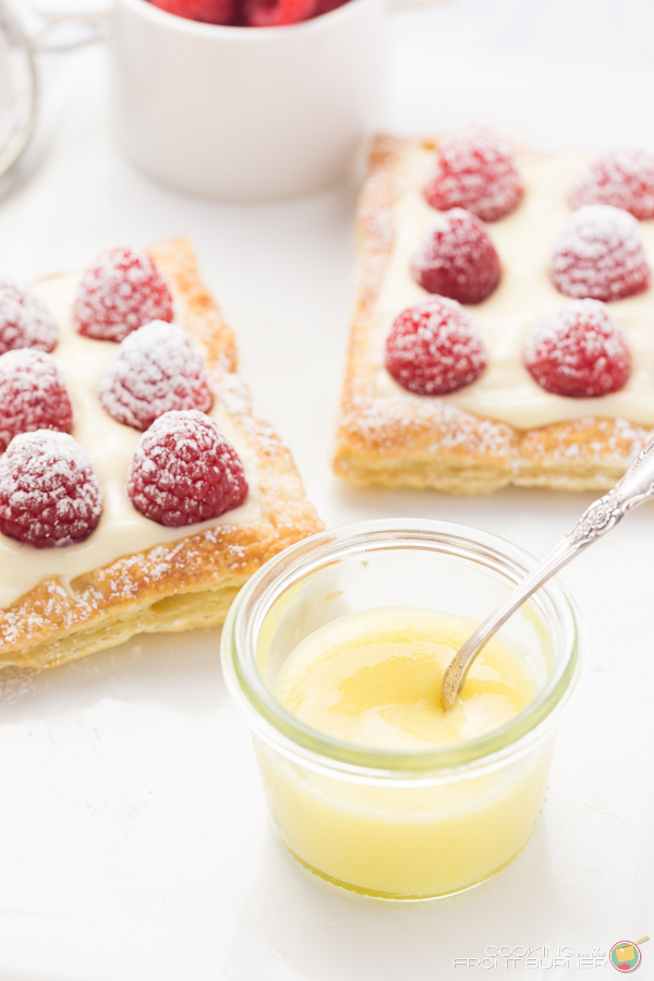 a cup with lemon curd and two raspberry lemon tarts
