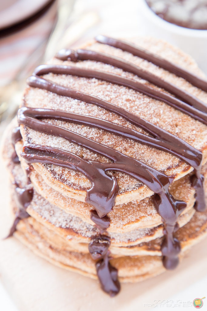 churro pancakes stacked with a chocolate syrup drizzled on top