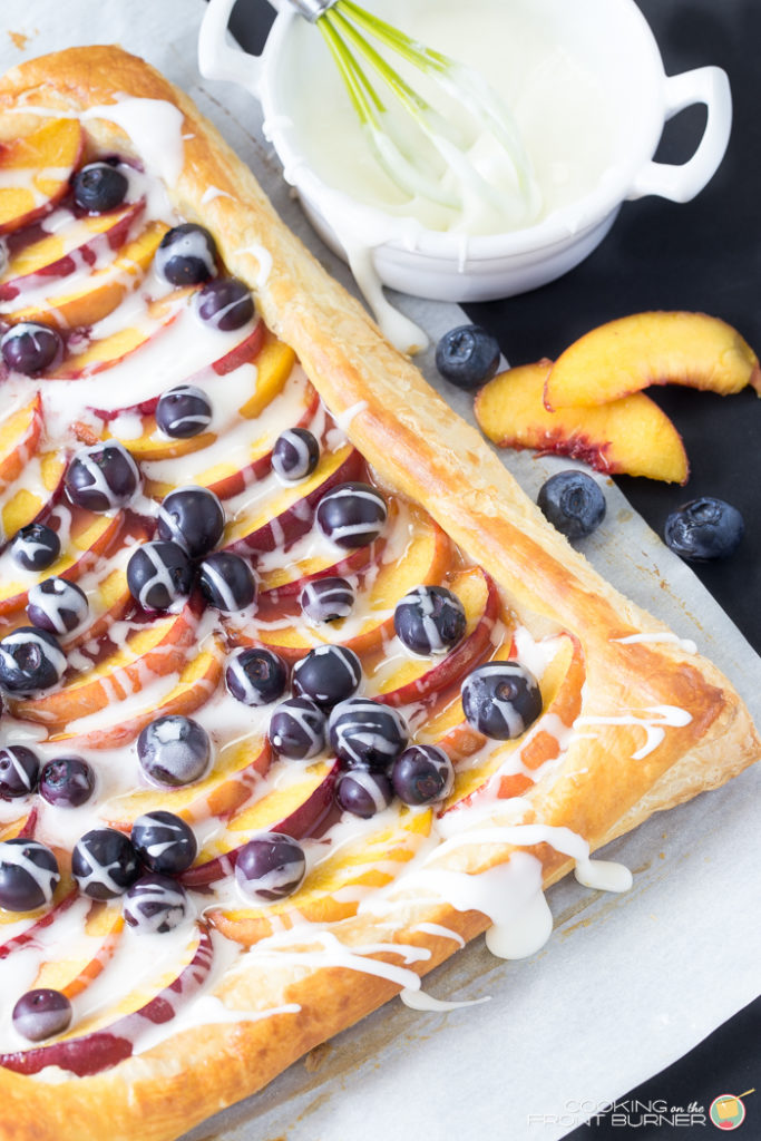 This delightful recipe is a light and flaky puffed pastry topped with fresh peaches, blueberries and creamy vanilla glaze. Fresh Peach and Blueberry Tart