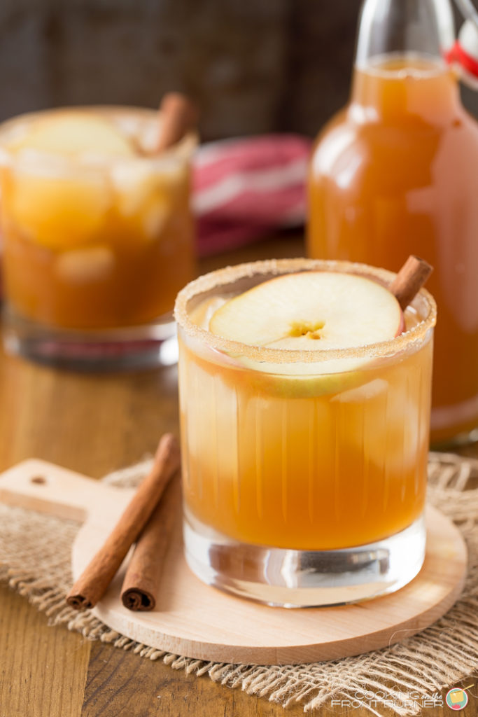 a short cocktail glass with an apple pie cinnamon cocktail in it with a apple slice on top