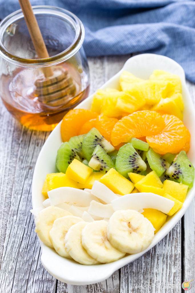 Breakfast granola tarts with creamy vanilla yogurt, topped with tropical fruits and drizzled with golden honey.