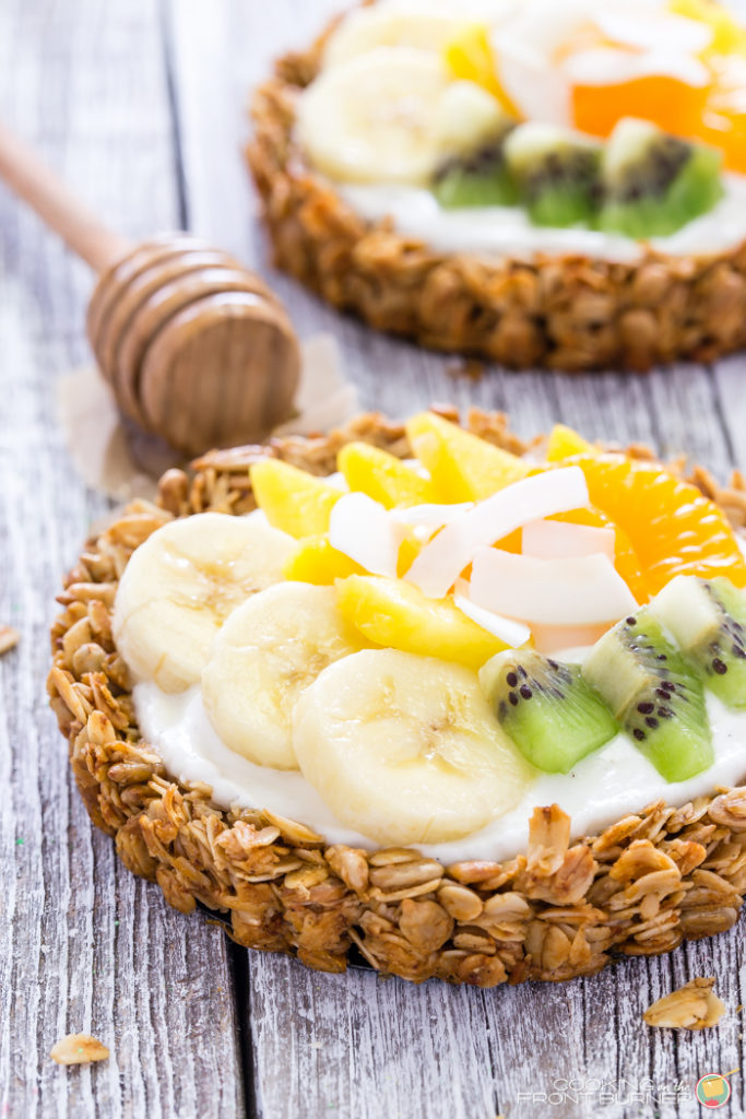 Breakfast granola tarts with creamy vanilla yogurt, topped with tropical fruits and drizzled with golden honey.