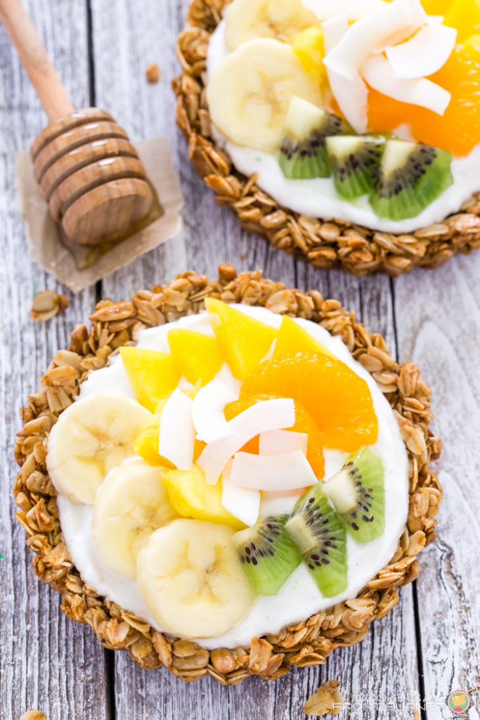 Breakfast granola tarts with creamy vanilla yogurt, topped with tropical fruits and drizzled with golden honey.