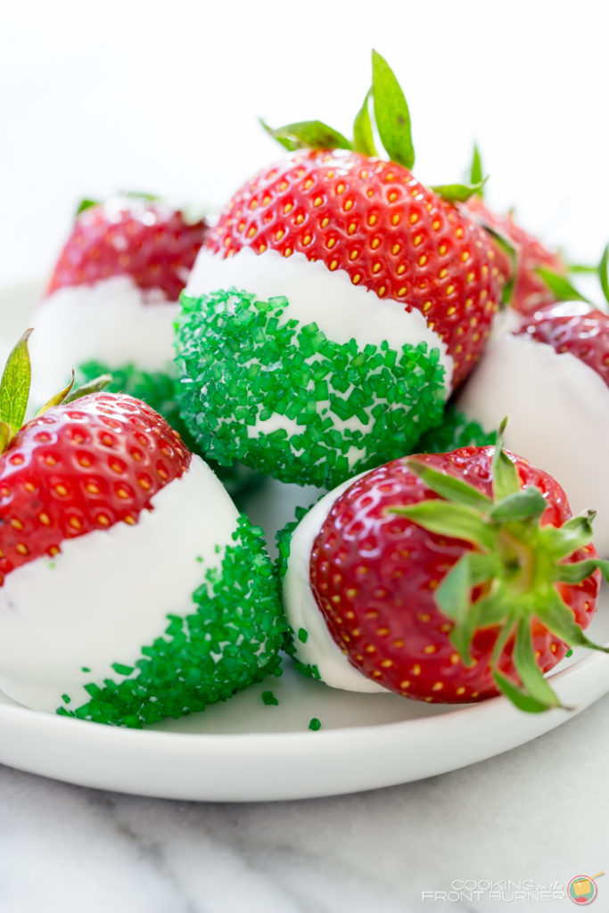 fresh strawberries that have dipped in white chocolate and topped with green sprinkles