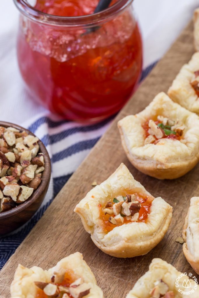 These Brie Pepper Jelly Bites are a great recipe to have on hand for the holidays!  You will love the flaky crust with brie and pepper jelly nestled inside.  Top with crunchy pecans and some green onions for a flavor explosion!