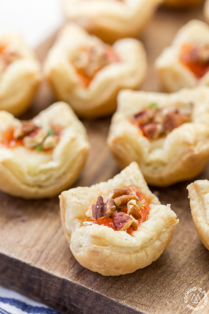 one puff pastry appetizer with brie and hot pepper jelly on a cutting board