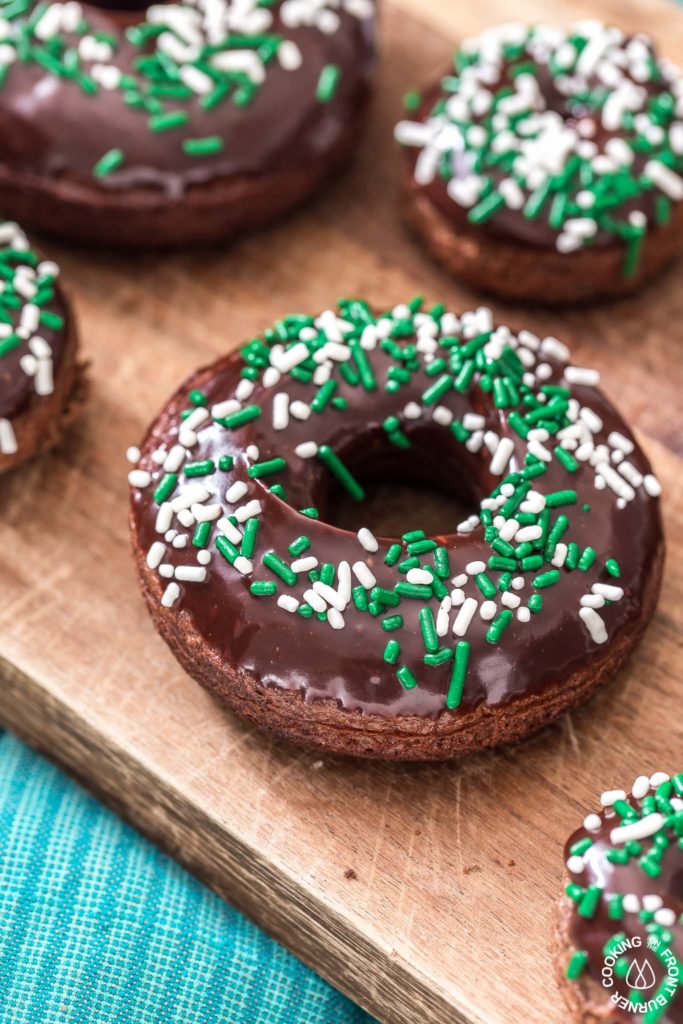 These chocolate Irish Cream Glazed Donuts are baked - not fried - and have a thick layer of chocolate ganache and festive sprinkles.  They are so easy to make and are perfect for breakfast for a sweet treat! #donuts #chocolate #ganache #irishcream #baked