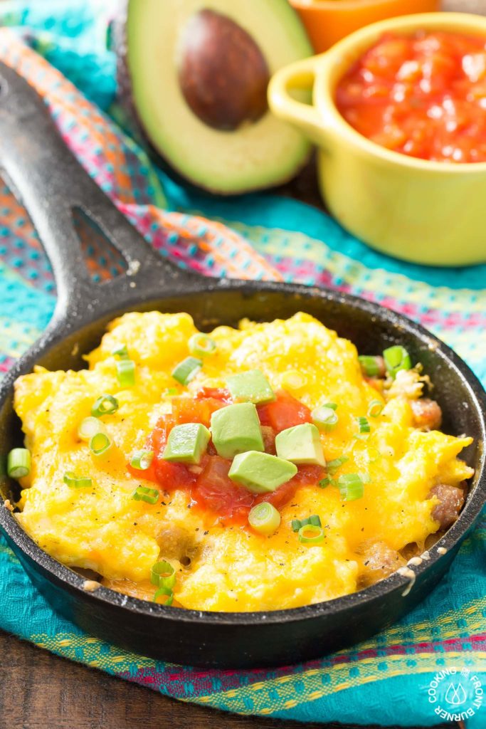You will love waking up to this Mexican Breakfast Skillet Pizza that will be your favorite meal of the day! The skillet is lined with crispy tator tots, lots of gooey cheese, sausage, eggs, green chilies and great toppings. #mexican #skillet #breakfastpizza