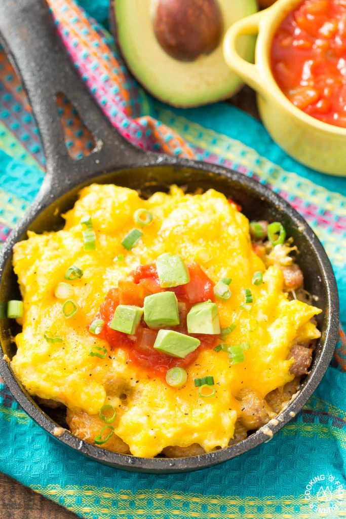 You will love waking up to this Mexican Breakfast Skillet Pizza that will be your favorite meal of the day! The skillet is lined with crispy tator tots, lots of gooey cheese, sausage, eggs, green chilies and great toppings. #mexican #skillet #breakfastpizza