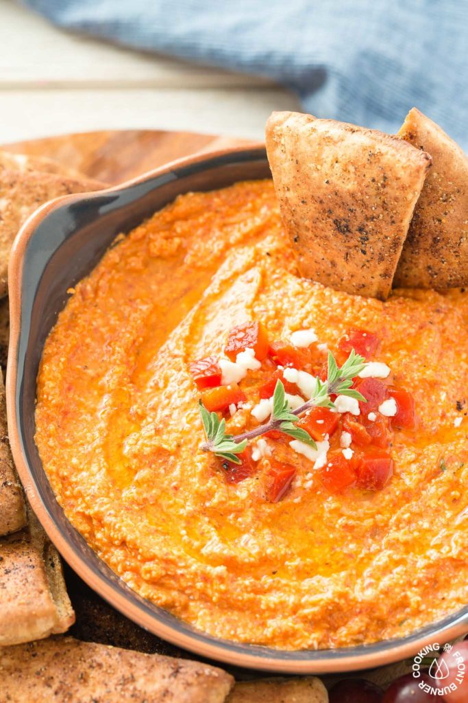 This Roasted Red Pepper Dip is an easy as throwing all the ingredients in a food processor, giving it a 30 second whirl and on your table in no time.  The Mediterranean flavors are perfect with toasted pita bread that you can also season up and bake as dippers. #redpepperdip #appetizer