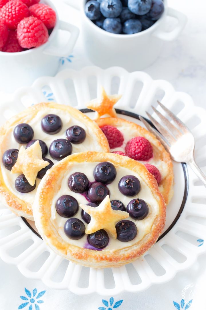 Start the day with these Breakfast Fruit Pastries with flaky puffed pastry, creamy lemon filling and topped with your favorite fruits. They can be on the table in no time and then watch them disappear! #puffedpastry #breakfast #fruitpastry Fruit pastry on a plate with blueberries and a star made out of puff pastry