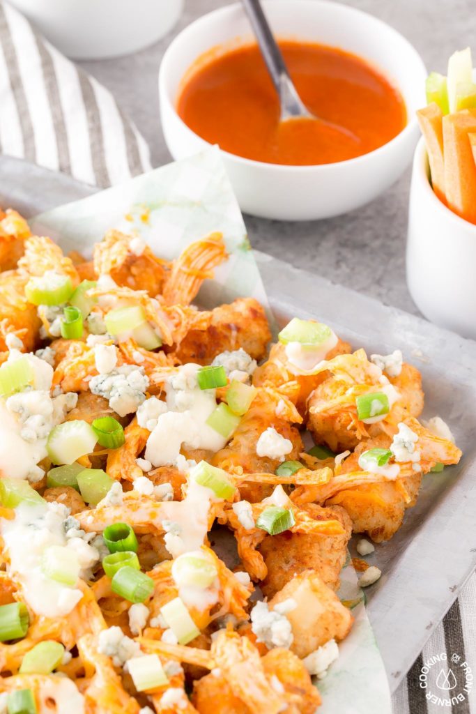 tator tots on a platter topped with blue cheese