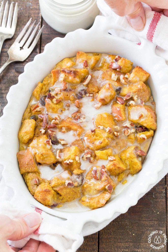 hands holding a baking dish of pumpkin spice bread pudding