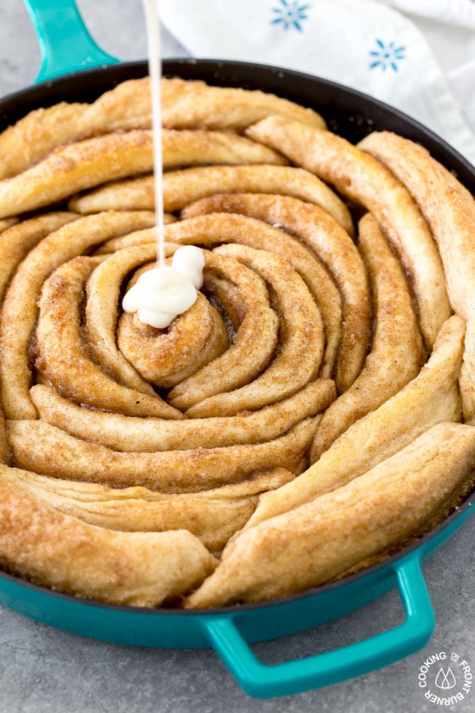 Cream cheese glaze being poured on baked bicuits