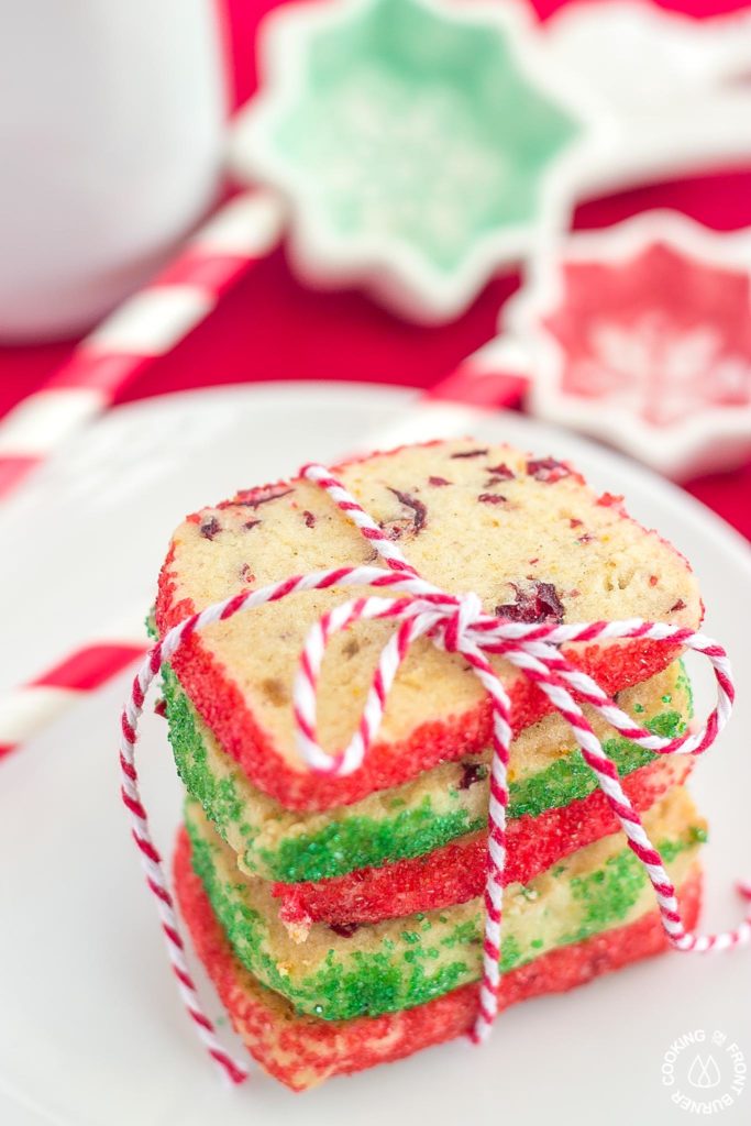 These shortbread Cranberry Orange Spice Cookies are sure to become a family favorite for the holidays. The combination of the crystallized ginger, dried cranberries and fresh orange peel are a tastebud delight! 4 cookies tied with a string on a plate