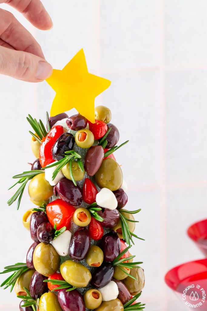 adding a yellow pepper star to an olive tree appetizer