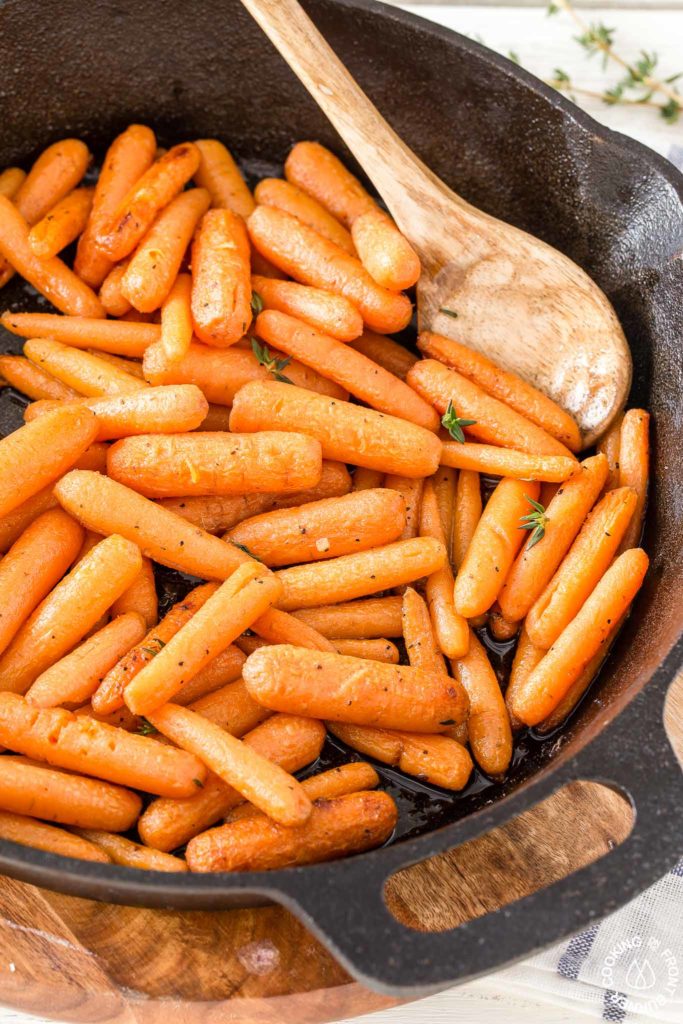 glazed carrots in a skillet with a serving spoon