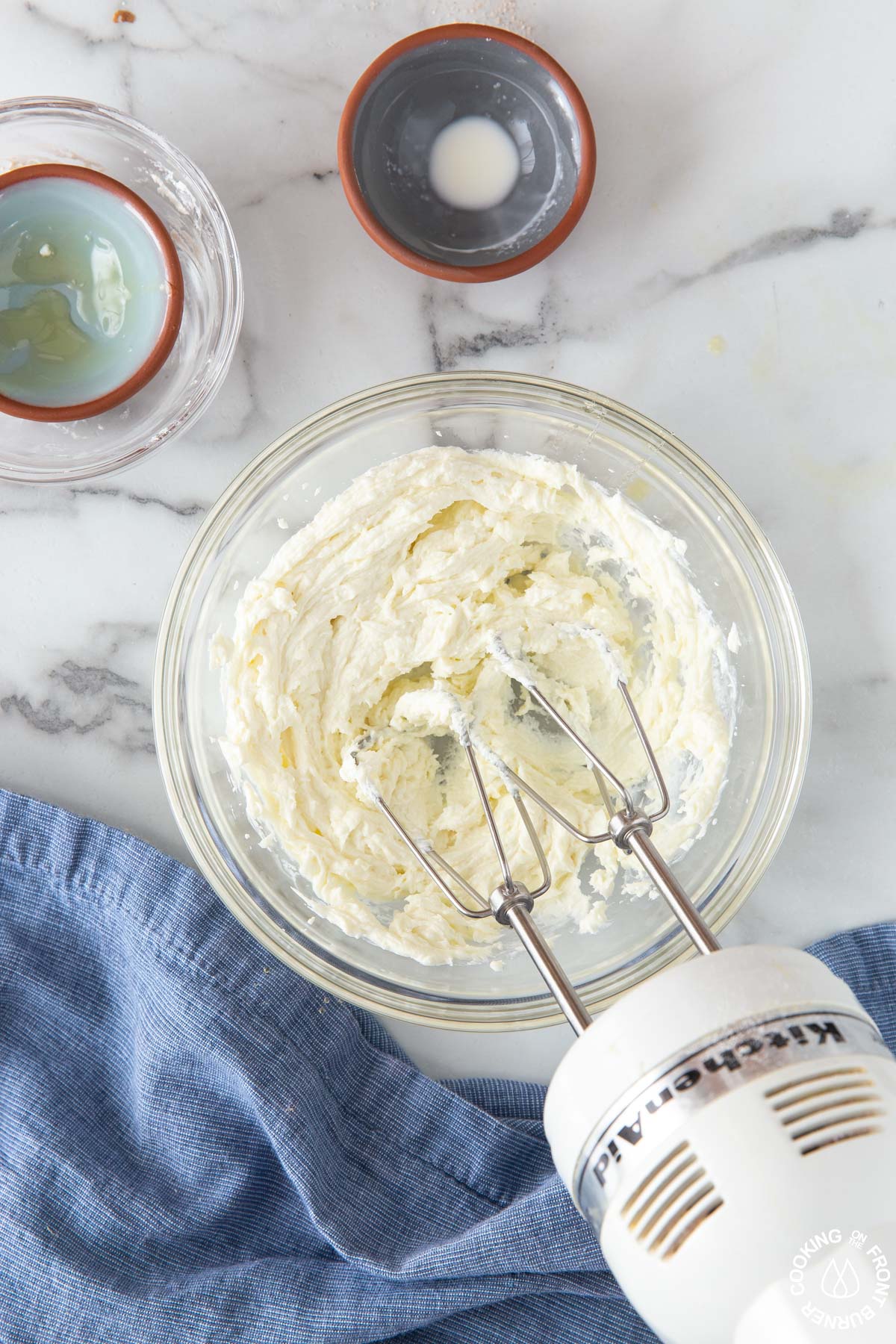 a bowl with goat cheese, honey heavy cream with a mixer