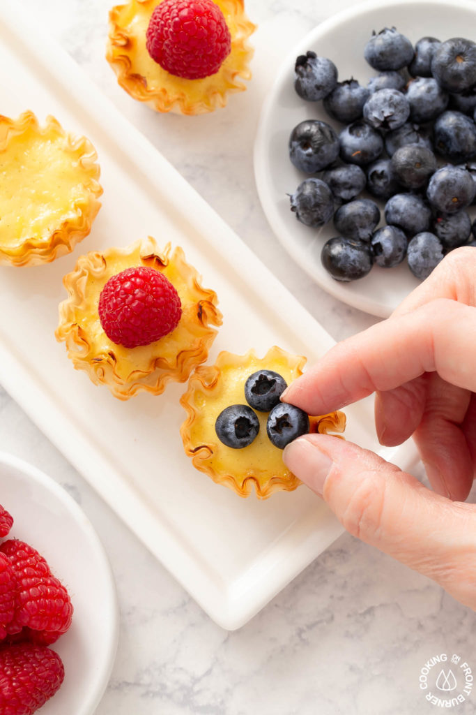 placing a blueberry on a lemon tart