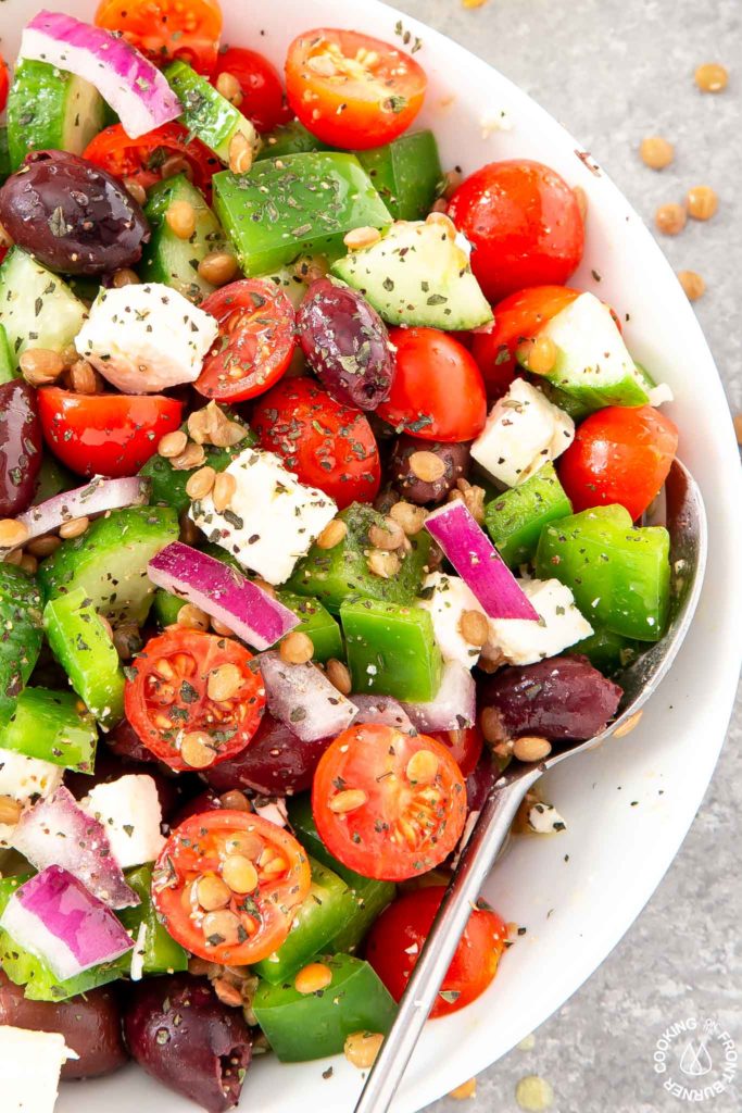 a bowl with greek salad mixed up with a spoon