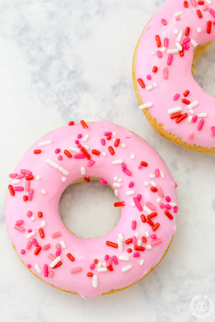 a baked vanilla donut with pink icing and sprinkles