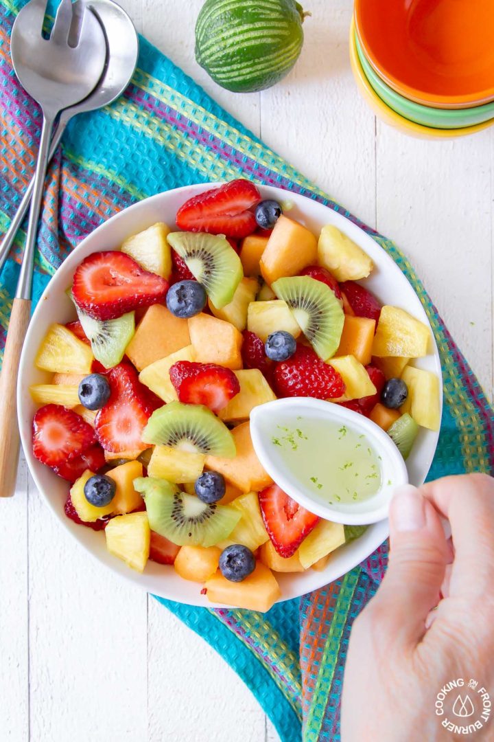 fresh fruit in a white bowl with utensils next to it