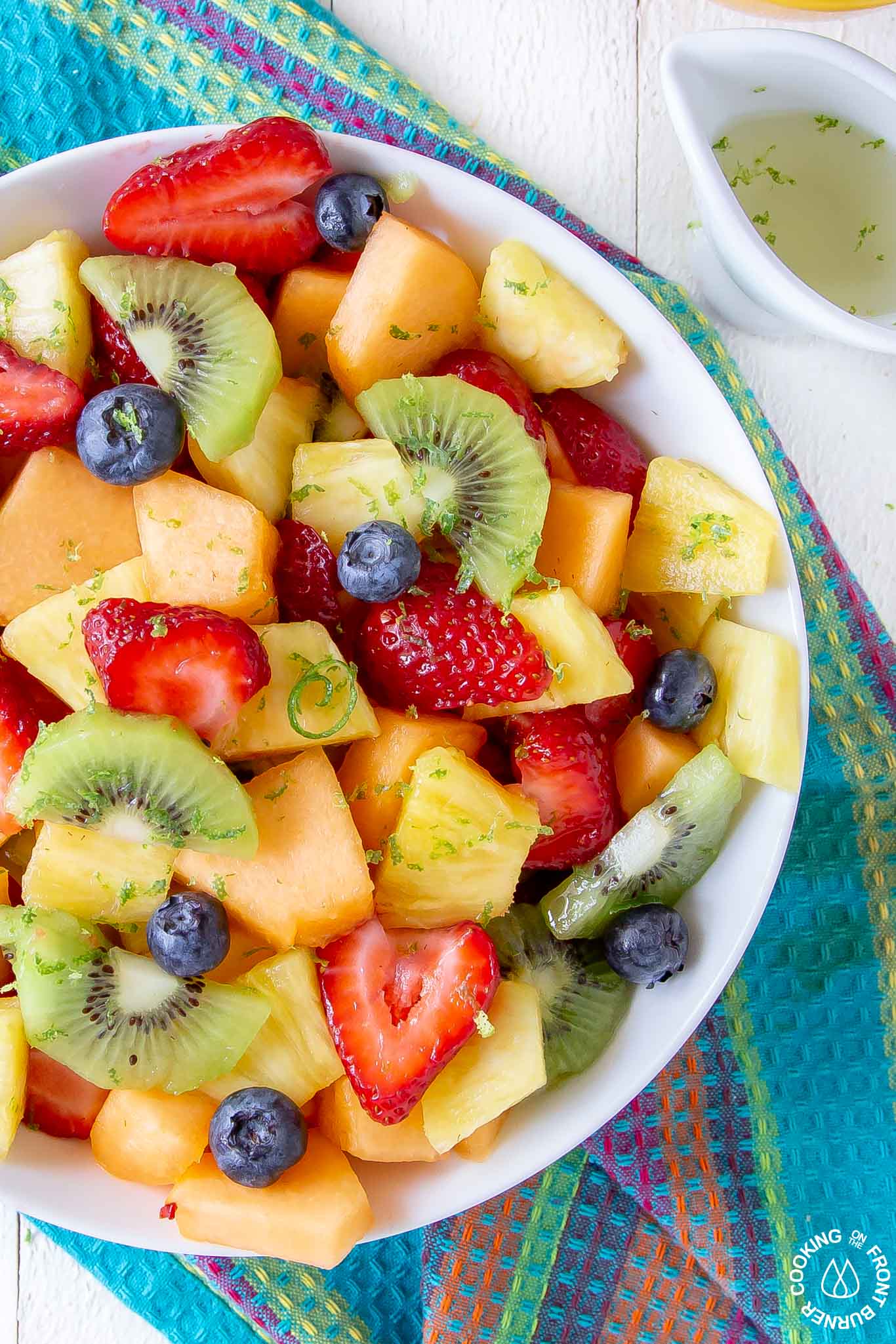 fruit salad in a white bowl topped with lime zest dressing