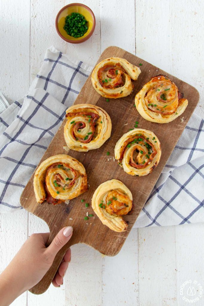 6 puff pastry ham cheese appetizers on a cutting board