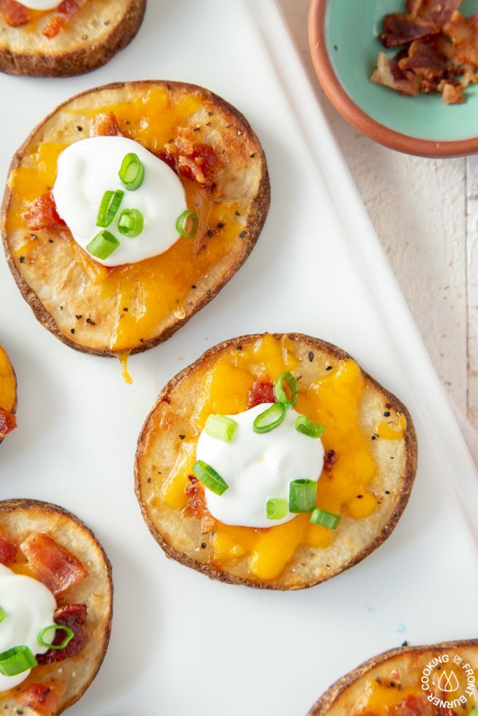 close up of loaded potato rounds on a white platter