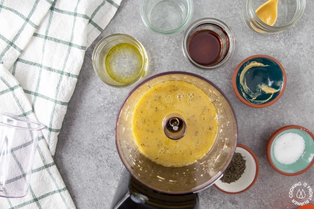 a close up shot of maple mustard vinaigrette in a food processor