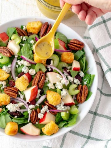 chopped spinach salad in a bowl with a drizzle of maple vinaigrette