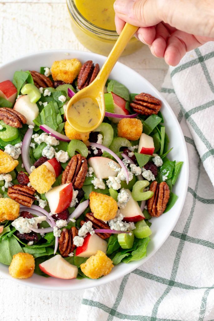 chopped spinach salad in a bowl with a drizzle of maple vinaigrette