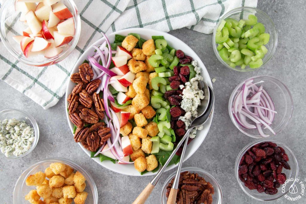 an overhead shot of a spinach and apple salad in a bowl