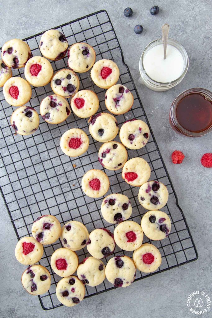 mini pancake muffins on a cooling rack with a side of glaze and maple syrup