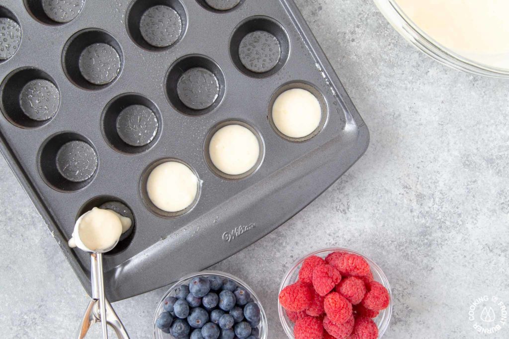 scooping pancake batter into mini muffin pan