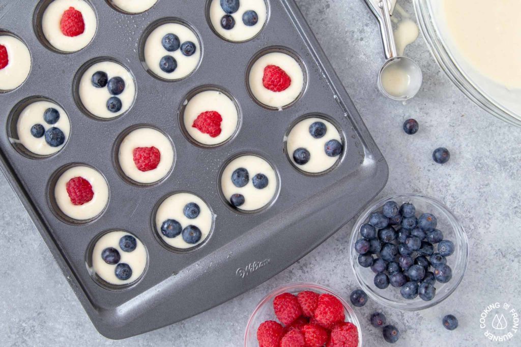 mini muffin pan with batter and topped with blueberries and raspberries