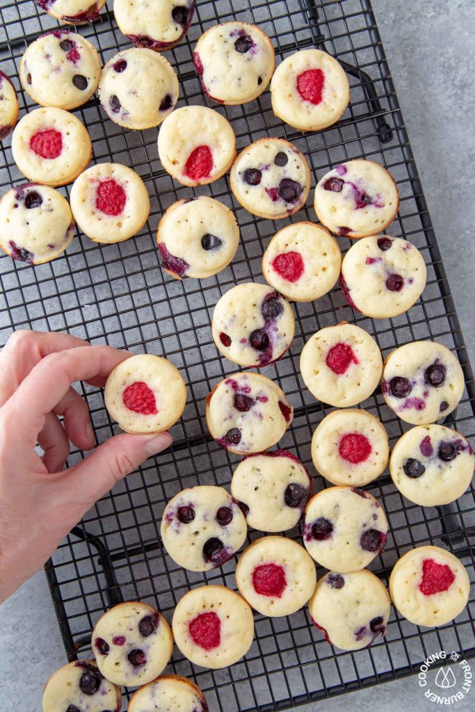 a hand taking a mini pancake muffin off a baking rack