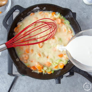 adding half and half to a skillet to make chicken pot pie