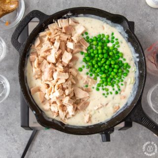 adding peas and cooked chicken to a skillet to make chicken pot pie