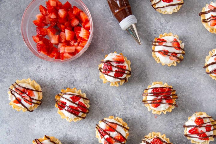 strawberry cheesecake tarts with chocolate drizzled on top