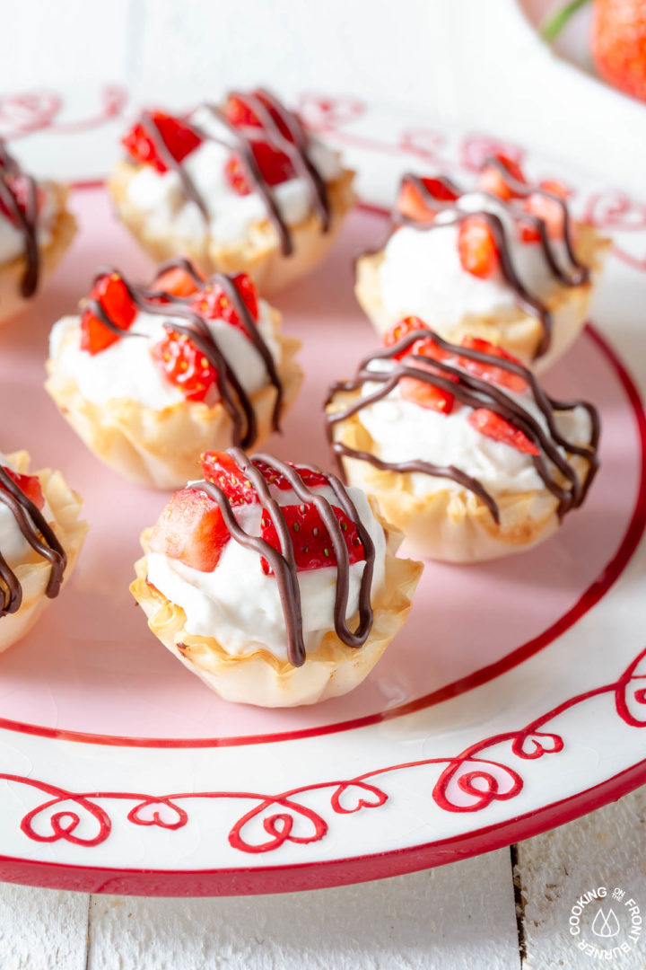 a close up shot of a strawberry cheesecake tart on a plate