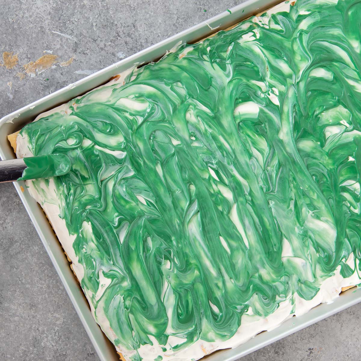 swirling green melted chocolate on top of white chocolate for toffee bars