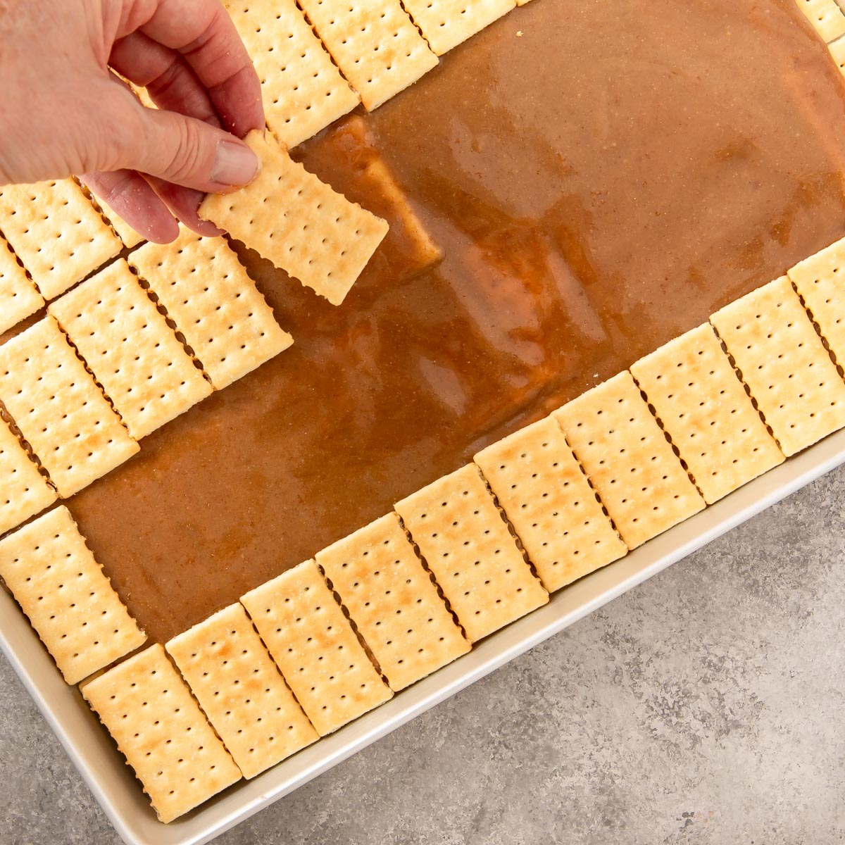 placing a second row of crackers on top of toffee mixture