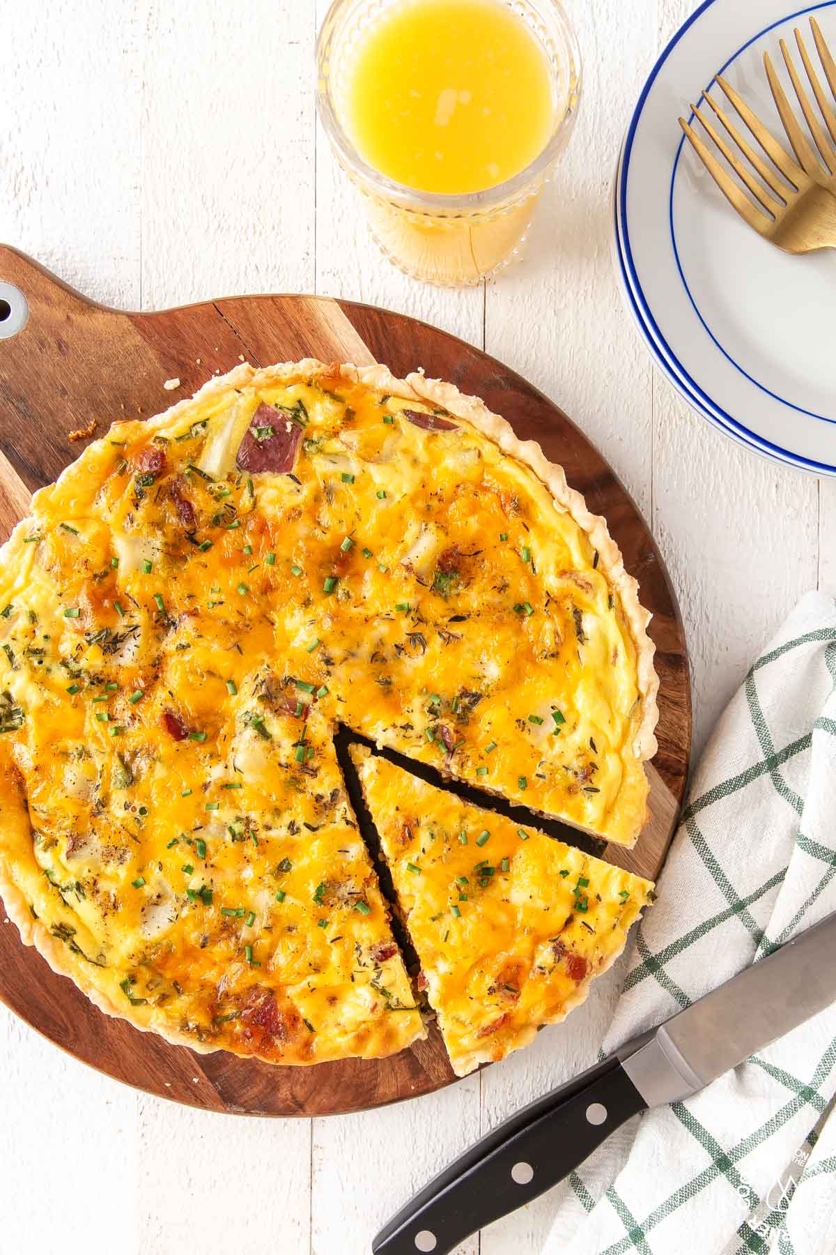 loaded baked potato quiche on a board with a slice cut out