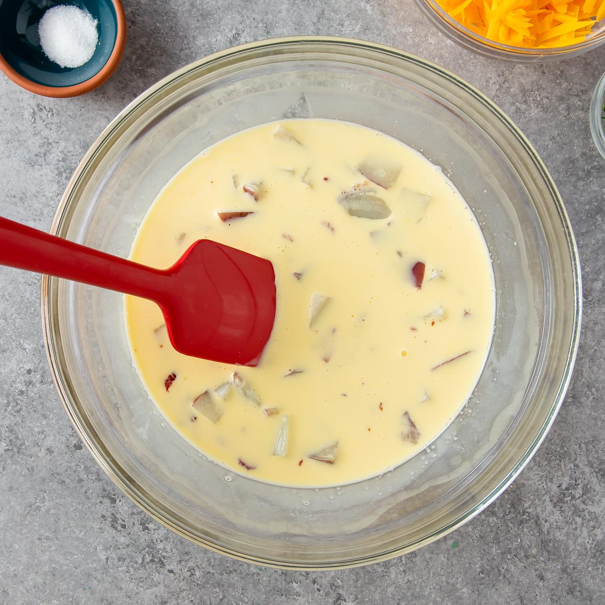 stirring potatoes, bacon with quiche egg mixture